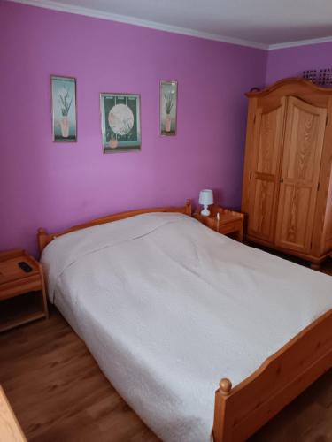 a bedroom with a bed and a purple wall at La Dolche Villa in Szőlősgyörök