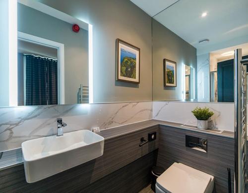 a bathroom with a sink and a toilet and a mirror at Hotel 30 Five in Aberdeen