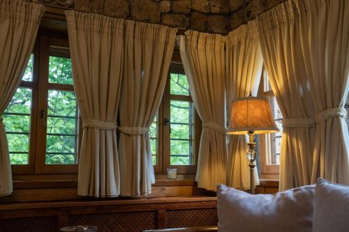 ein Schlafzimmer mit Vorhängen, einer Lampe und Fenstern in der Unterkunft Roes Suites in Kato Loutraki