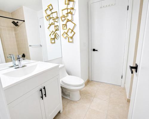 a white bathroom with a toilet and a sink at 2 Bedroom Condo With City Views and Free Parking in Toronto