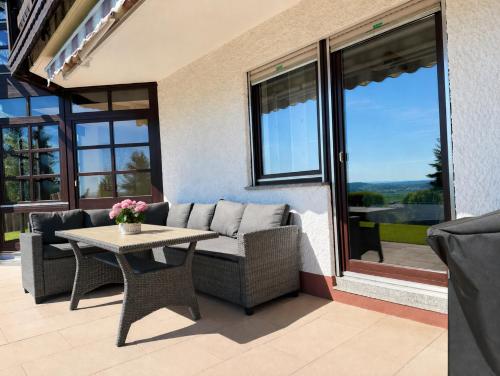 a patio with a couch and a table and windows at Apartment Kneer - Panoramic View & Private Garden near Black Forest & Lake Constance in Donaueschingen