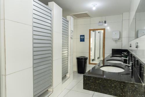 a bathroom with three sinks and two mirrors at Manhatã Hostel in Salvador