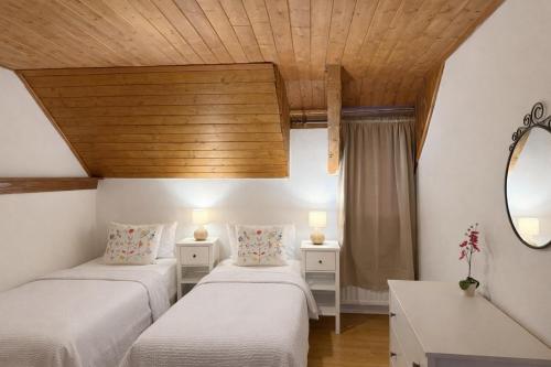 two beds in a room with a wooden ceiling at Rose Cottage in Bovec