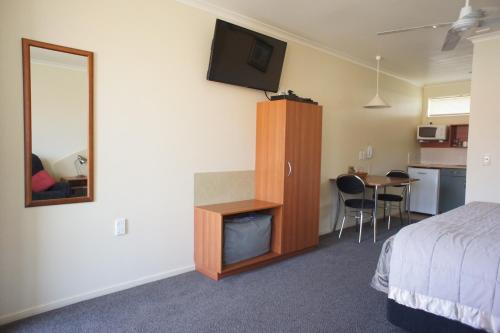 a hotel room with a bed and a cabinet with a television at Bks Egmont Motor Lodge in New Plymouth
