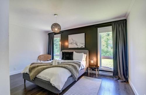 a bedroom with a large bed and two windows at Käbane Kozya - La Rassembleuse in Les Éboulements