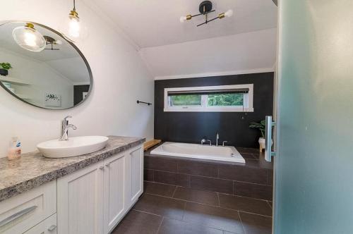 a bathroom with a sink and a tub and a mirror at Käbane Kozya - La Rassembleuse in Les Éboulements