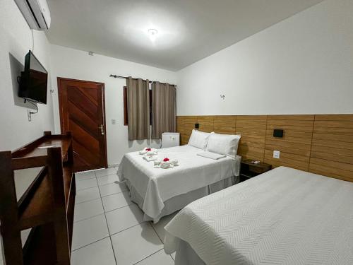 a hotel room with two beds and a television at Pousada Villa Galinhos in Galinhos
