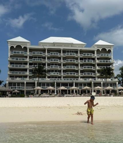 a man standing in the water in front of a hotel at Apartment with Exclusive Amenities in George Town
