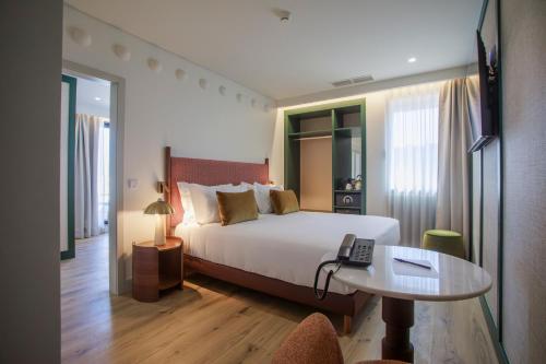 a hotel room with a bed and a phone on a table at Casa Falcão Boutique Hotel by Aspasios in Porto