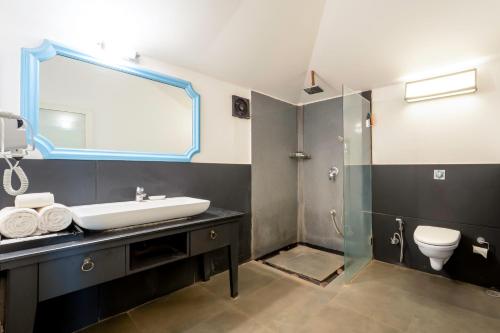 a bathroom with a sink and a toilet and a mirror at Marbela Beach Resort in Morjim