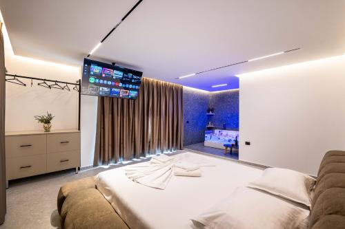 a bedroom with a large bed with a tv on the wall at Euphoria Apartments in Sarandë