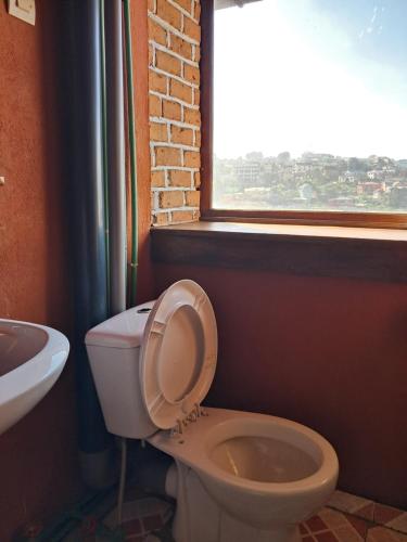a bathroom with a toilet and a window at Hotel Anjara in Ambositra