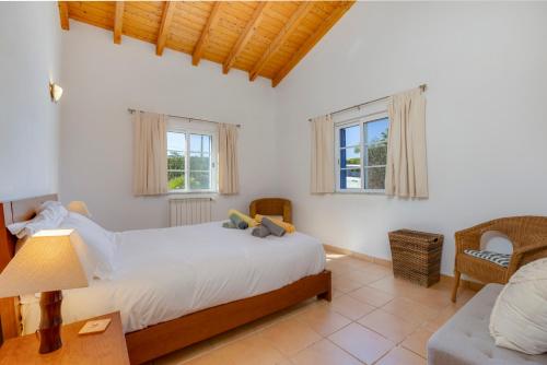 a bedroom with a bed and a couch and two windows at Vila Fantastica in Aljezur