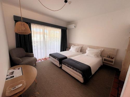a hotel room with two beds and a chair at Pátio das Ribeiras in Almeirim