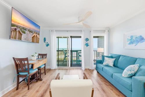 a living room with a blue couch and a table at Tide Time Oceanfront at Sea Cabin w Pool in Myrtle Beach