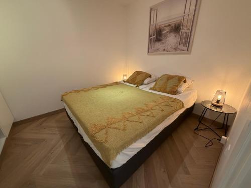 a bedroom with a bed and a table with a lamp at Beachday II - Opkuis inbegrepen in de prijs - Garagebox inbegrepen in Nieuwpoort