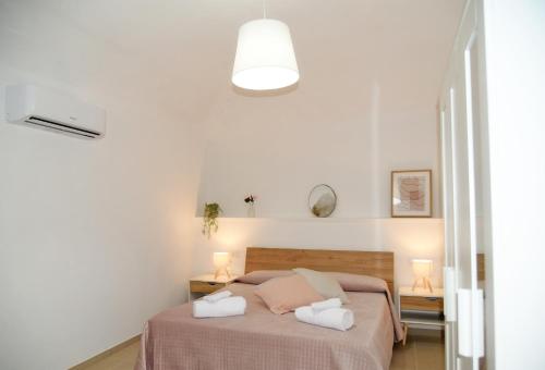 a white bedroom with a bed with two pillows at DOMUS Canonico in Noto