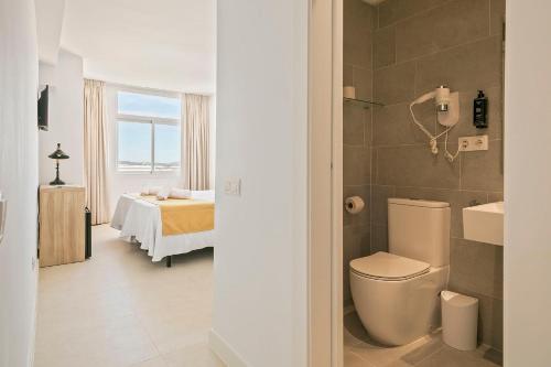 a bathroom with a toilet and a bedroom with a bed at Suncoast Ibiza Hotel - Adults Only - in Ibiza Town