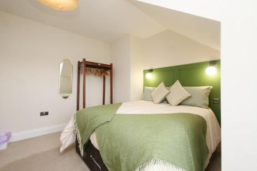 a bedroom with a bed with a green headboard at The Wheatley in Denton
