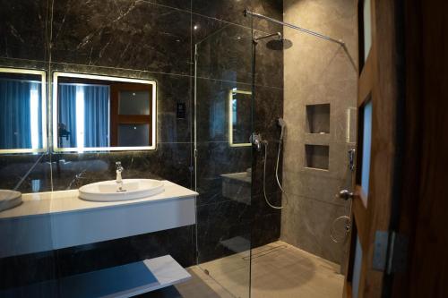 a bathroom with a sink and a shower with a glass door at Silverado Boutique Hotel in Tanga
