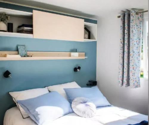 a bed with blue walls and white pillows at Cottage PARKS DI LICCIA in Bonifacio