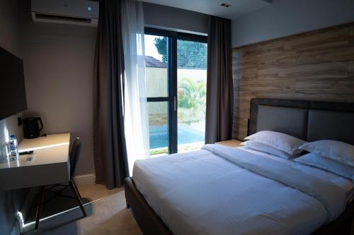a bedroom with a bed and a desk and a window at Silverado Boutique Hotel in Tanga