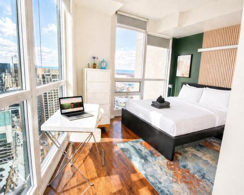 a bedroom with a bed and a desk with a laptop at 2 Bedroom Condo With City Views and Free Parking in Toronto