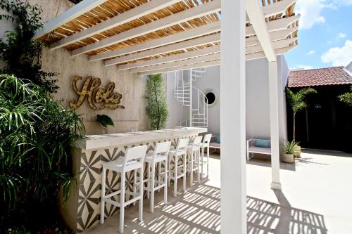 a patio with a white bar with white stools at The Diplomat Boutique Hotel in Mérida