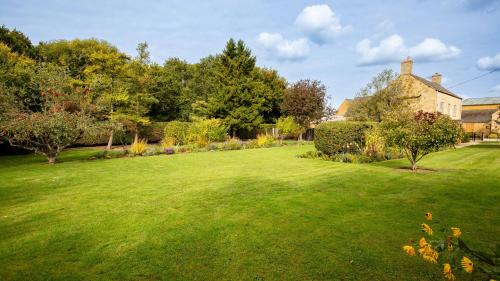 a large green yard with a house and trees at Lower Farmhouse in Todenham