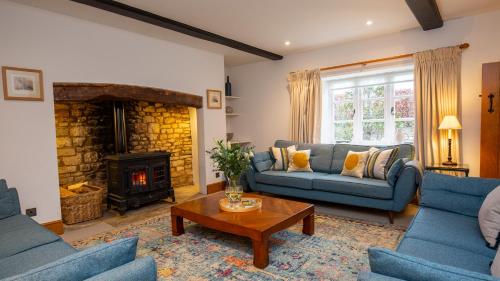 a living room with blue couches and a fireplace at Lower Farmhouse in Todenham