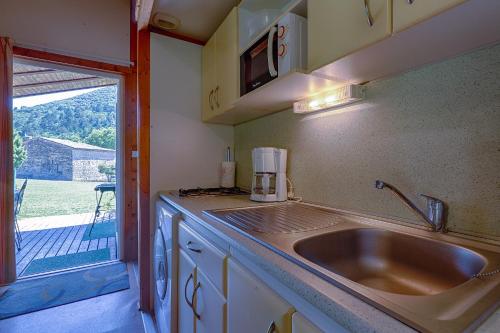 a kitchen with a sink and a view of a yard at Chalet D'alpion Nord avec Piscine in Les Tourrettes