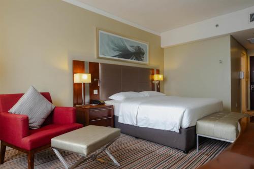 a hotel room with a bed and a red chair at Park Inn by Radisson, Kigali in Kigali
