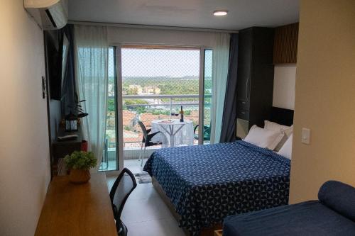a bedroom with a bed and a balcony with a table at Aurora Fortaleza in Fortaleza
