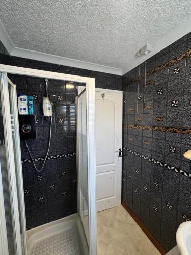 a bathroom with a shower with black walls at 2A Lochy Crescent in Inverlochy