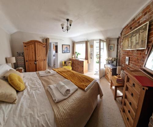 a bedroom with a large bed and a brick wall at The Old Dairy, comfy 1 bedroom apartment with lounge,bathroom and kitchenette near town, pubs and walks in Ringwood