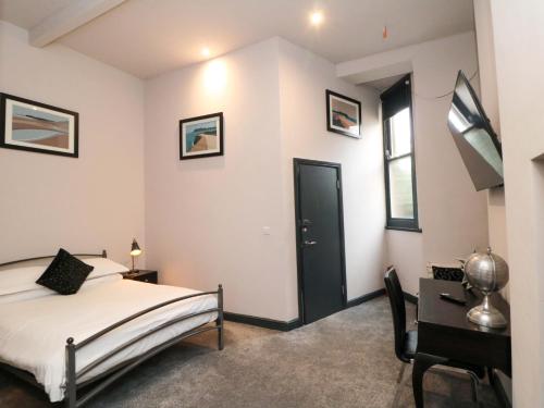 a bedroom with a bed and a desk and a window at Craven Suite in Scarborough