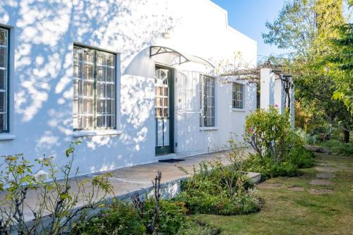 a white house with windows and a yard at Olive's Cottage in Molteno