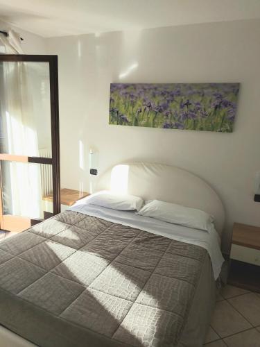 ein Schlafzimmer mit einem Bett und einem Gemälde an der Wand in der Unterkunft Lanterna Apartment 1 in Chiesa in Valmalenco