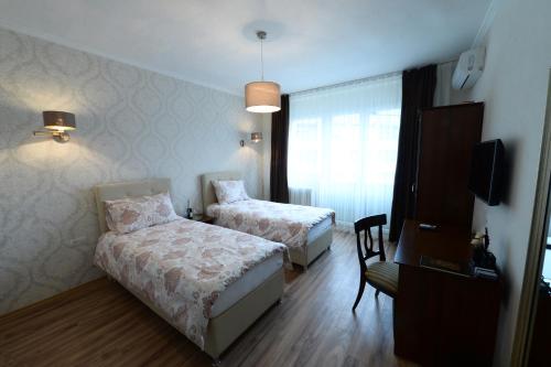 a hotel room with two beds and a chair at Calla Bella Rooms & Snack Bar in Skopje