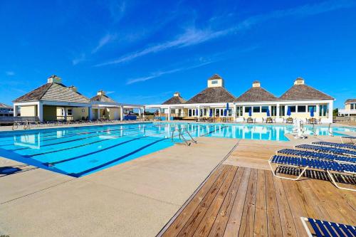 a large swimming pool with blue chairs and buildings at 6155 - Designed to Please in Nags Head