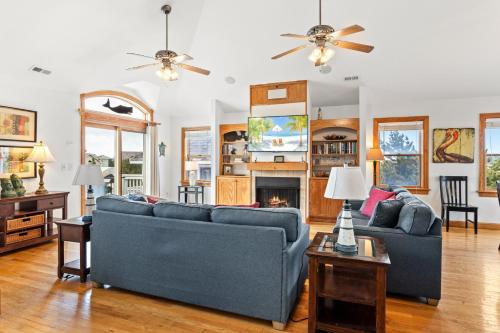 a living room with two blue couches and a fireplace at 6155 - Designed to Please in Nags Head