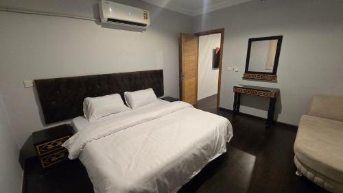 ein Schlafzimmer mit einem großen weißen Bett und einem Spiegel in der Unterkunft صدى التلال in As Sifyānī