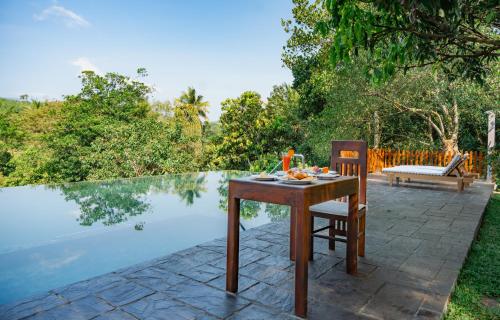 a table and chair sitting next to a pool at Kandy Neela Weralu in Haragama