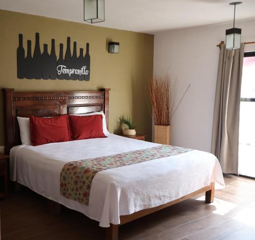 a bedroom with a large bed with red pillows at Hotel Casa de Vino in Tequisquiapan