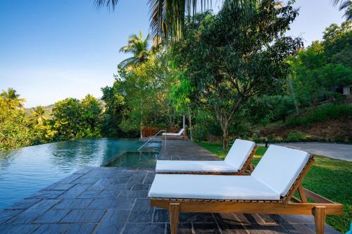 a pair of lounge chairs next to a swimming pool at Kandy Neela Weralu in Haragama