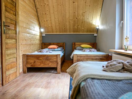two beds in a room with wooden walls at Domki Markowa Dolina in Rymanów