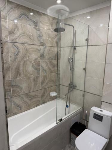 a bathroom with a shower and a toilet and a tub at ЖК Сити Парк in Osh