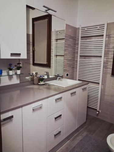 a white kitchen with a sink and a mirror at Respiro di Lago - Pool Friend in Paratico