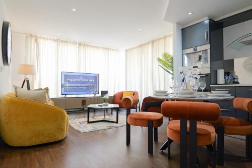 a living room with a table and chairs and a tv at Austin David Apartments ExCeL in London