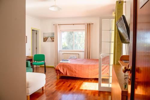 a bedroom with a bed and a green chair at Casa do Marmeleiro Guest House Cascais in Cascais